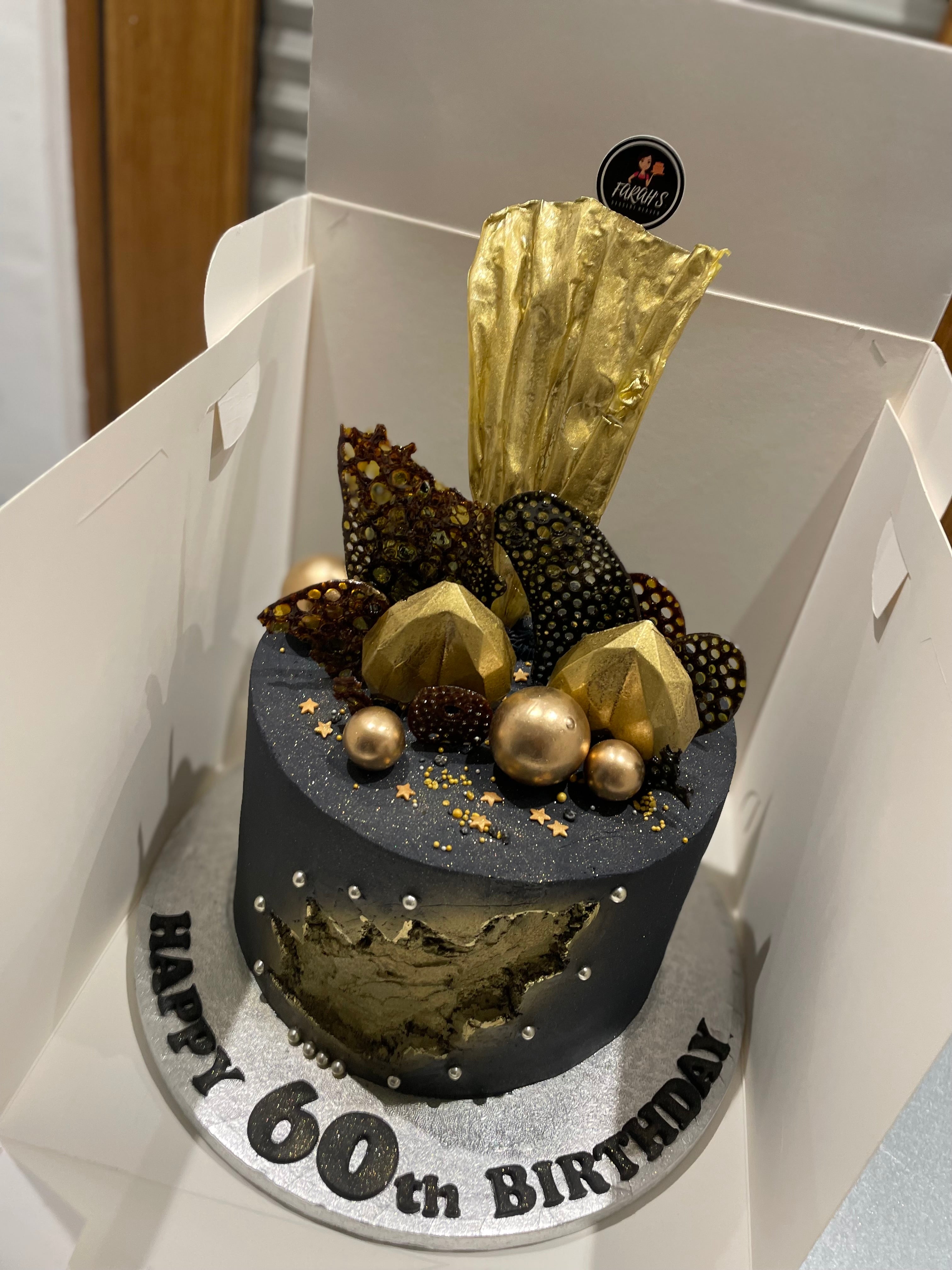 Black and gold two tier square cake with marbling and chocolate gold sail